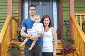 A Portrait of couple with their adorable daughter in front of house